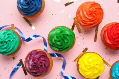 Photo of Flat lay composition with delicious colorful cupcakes and confetti on pink background