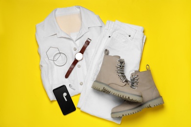Stylish boots, new clothes, smartphone and accessories on yellow background, flat lay