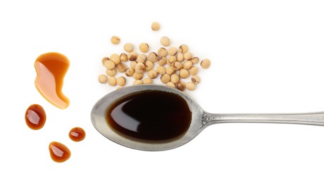 Photo of Tasty soy sauce in spoon and soybeans isolated on white, top view