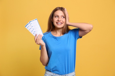 Photo of Portrait of happy young woman with lottery tickets on yellow background
