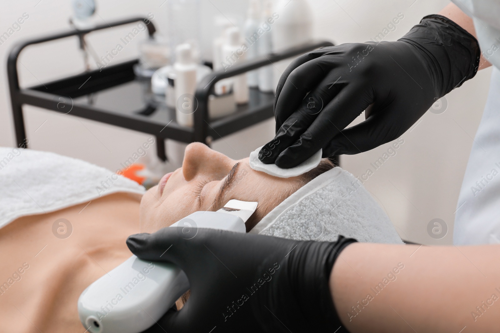 Photo of Cosmetologist using ultrasonic scrubber, closeup. Client having cleansing procedure in clinic