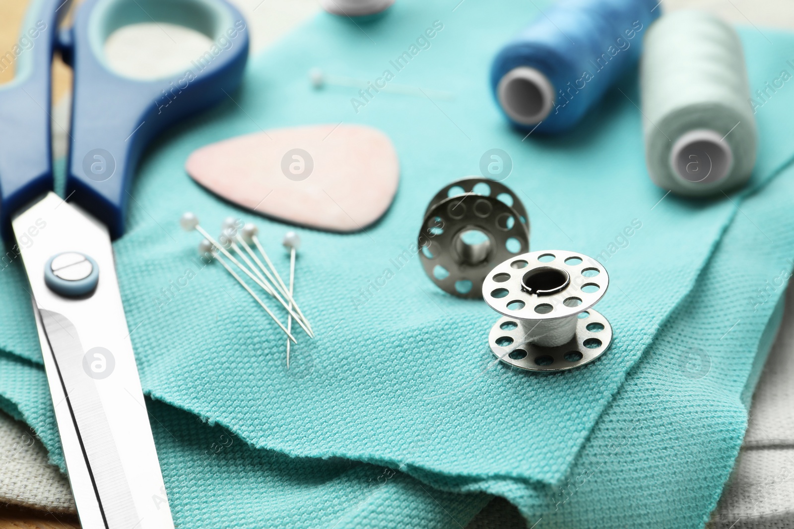 Photo of Scissors, spools of threads and sewing tools on cloth, closeup