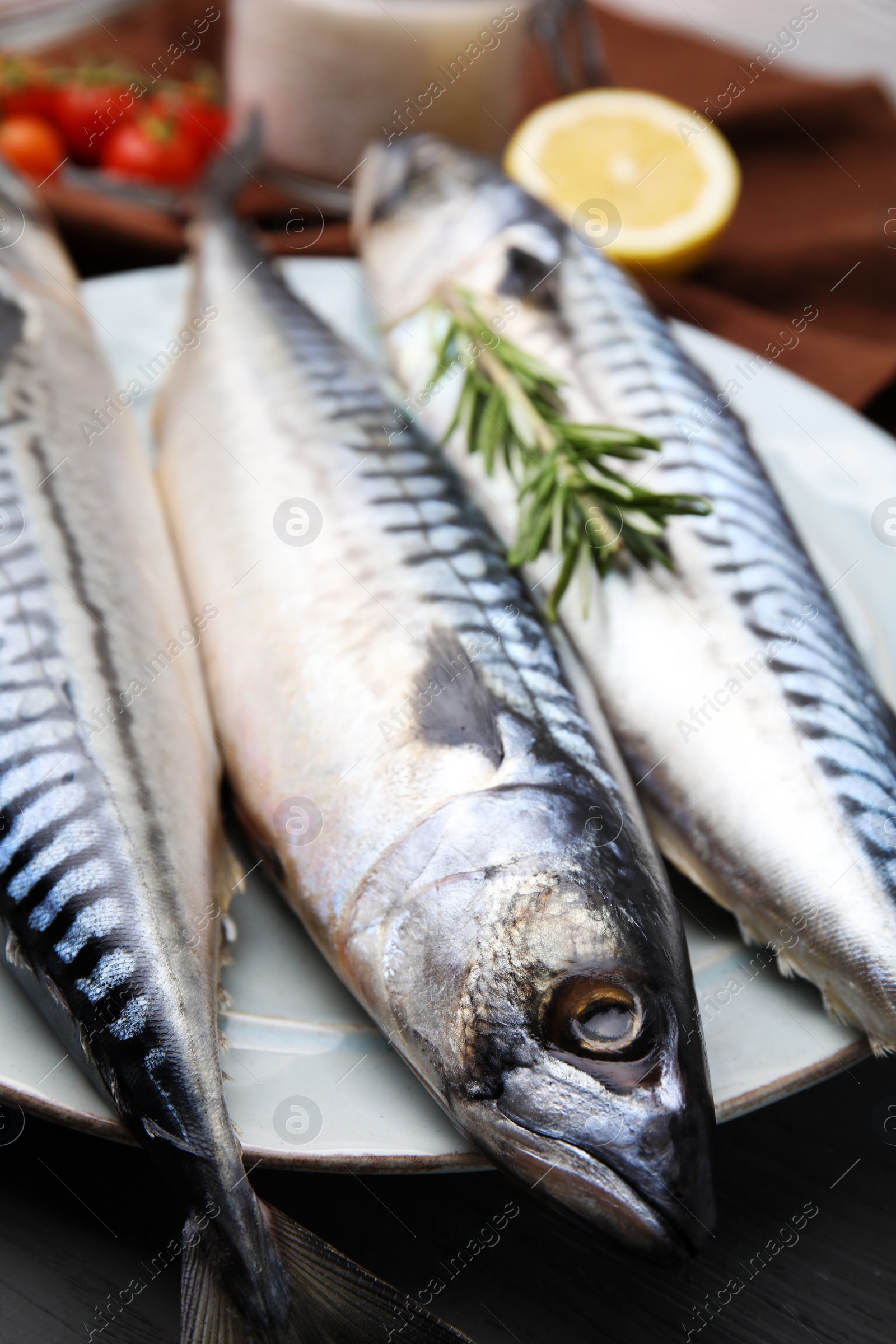 Photo of Raw mackerel and rosemary on black wooden table