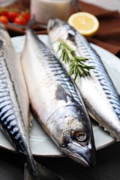 Photo of Raw mackerel and rosemary on black wooden table