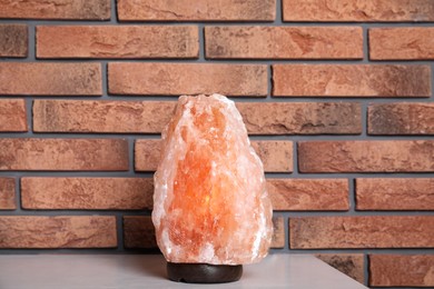 Photo of Himalayan salt lamp on table near brick wall