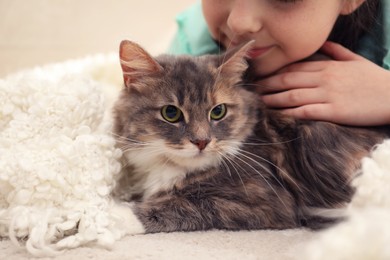 Photo of Cute little girl with cat indoors, closeup. First pet