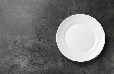 Photo of Clean white plate on grey table, top view. Space for text