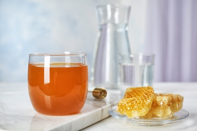 Photo of Glass of honey and honeycombs on table