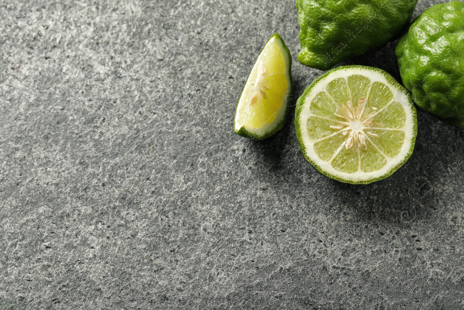 Photo of Whole and cut ripe bergamot fruits on grey table, flat lay. Space for text