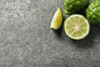 Photo of Whole and cut ripe bergamot fruits on grey table, flat lay. Space for text