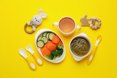 Photo of Healthy baby food in bowls and accessories on yellow background, flat lay