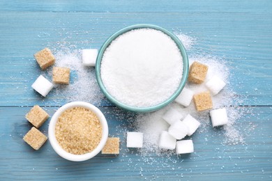 Different types of sugar on light blue wooden table, flat lay