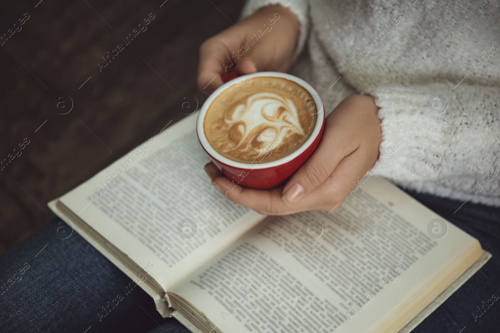 Photo of Woman with cup of coffee reading book at home, closeup