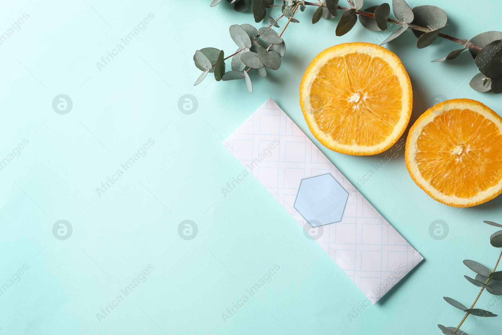 Photo of Scented sachet, eucalyptus branches and halves of orange on turquoise background, flat lay. Space for text