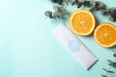 Photo of Scented sachet, eucalyptus branches and halves of orange on turquoise background, flat lay. Space for text