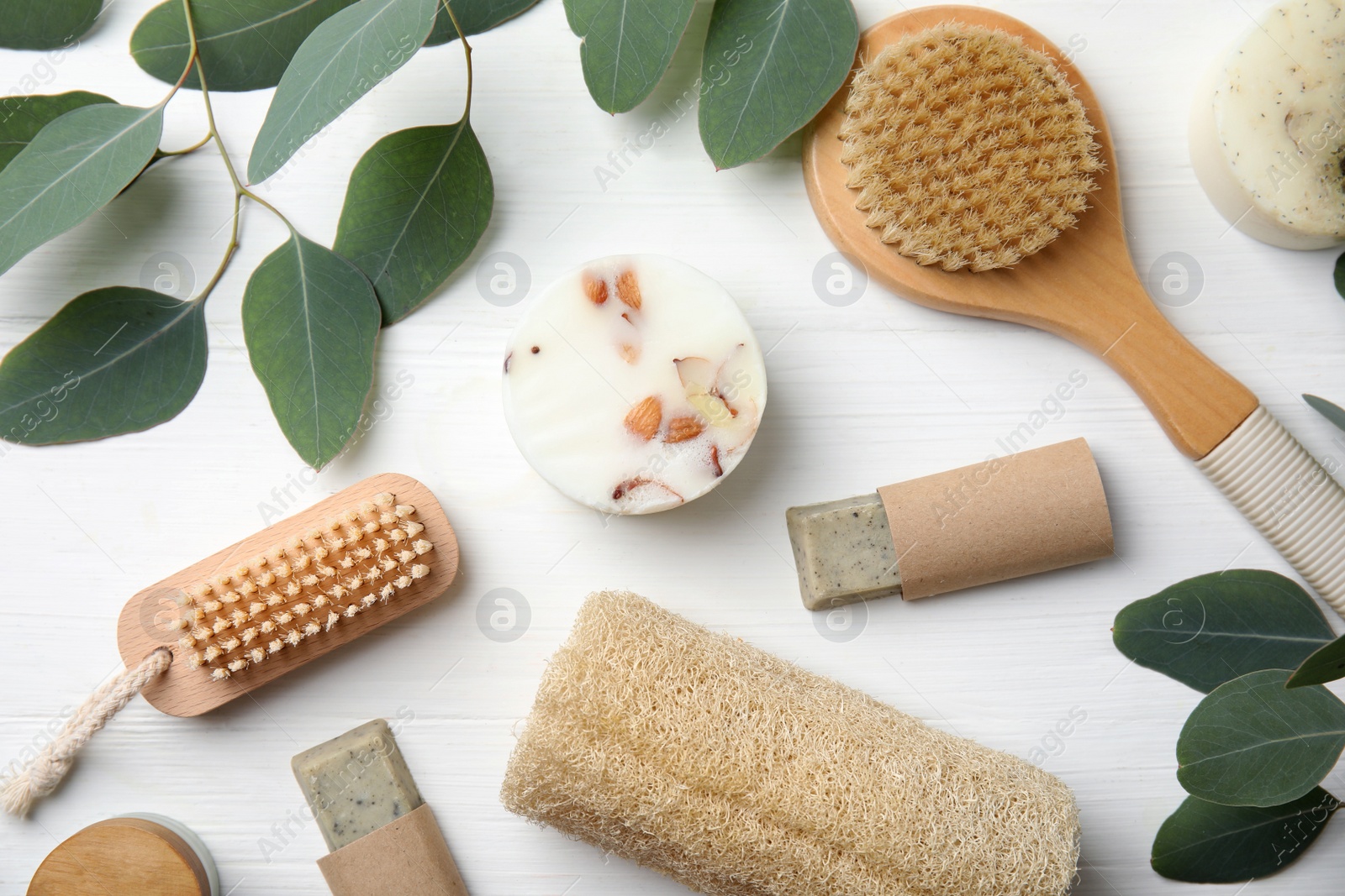 Photo of Eco friendly personal care products and leaves on white wooden table, flat lay