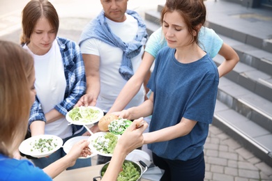 Volunteers serving food for poor people outdoors