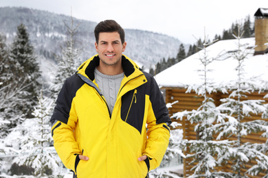 Photo of Happy man near snowy fir trees. Winter vacation