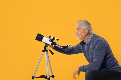 Photo of Senior astronomer with telescope on yellow background