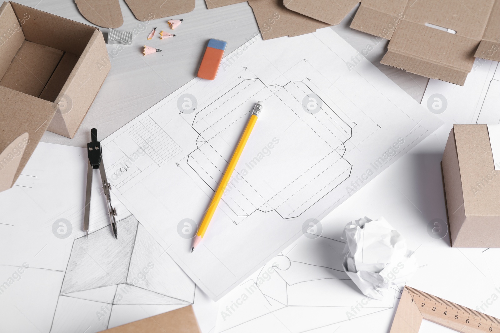 Photo of Creating packaging design. Drawings, boxes and stationery on light wooden table, above view