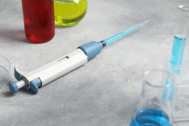 Laboratory analysis. Micropipette and glassware with liquids on grey table