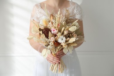 Photo of Bride holding beautiful dried flower bouquet at home, closeup