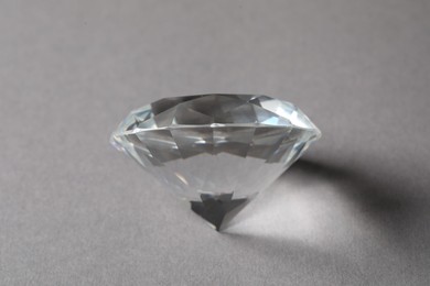 Photo of Beautiful dazzling diamond on grey background, closeup