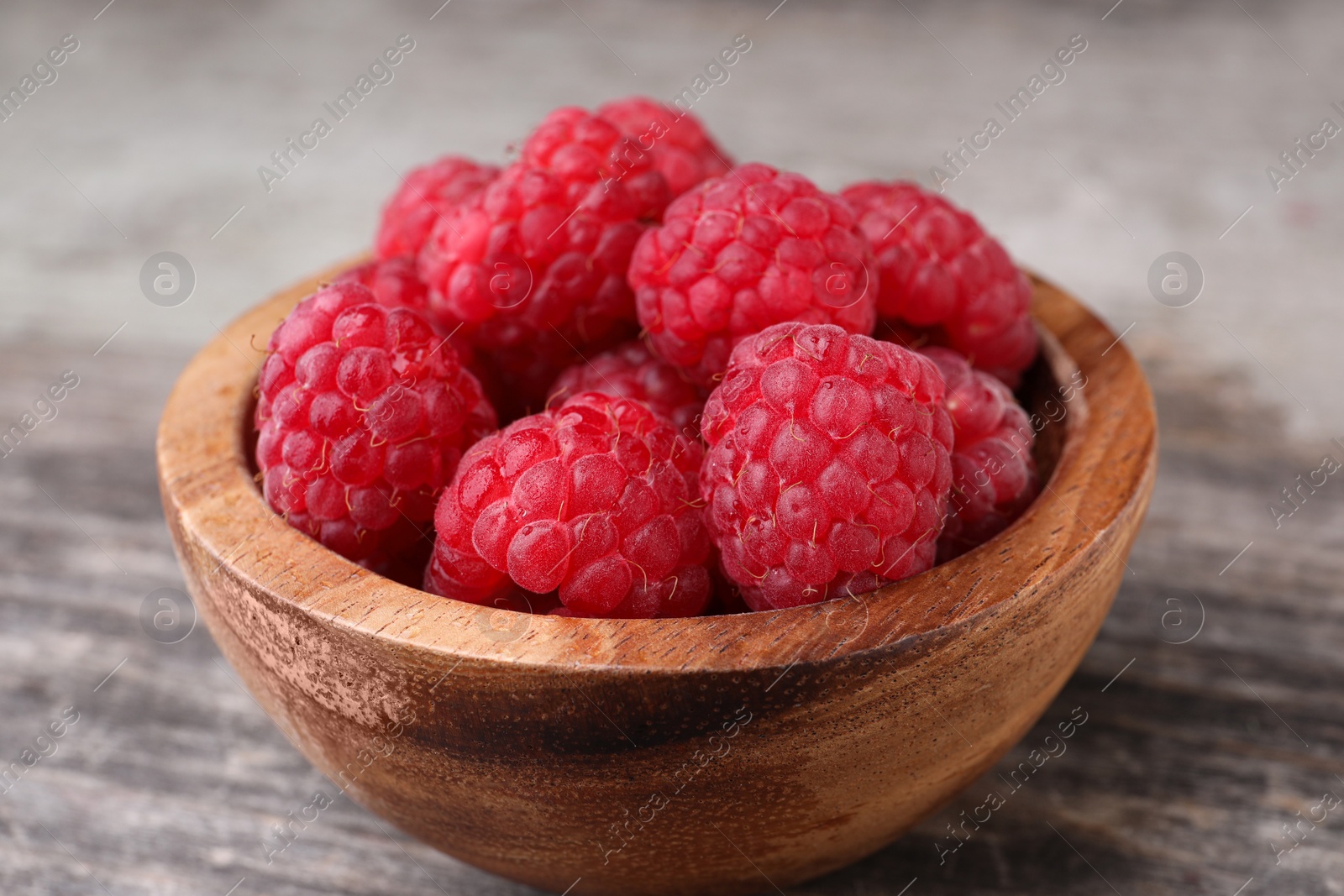 Photo of Tasty ripe raspberries in bowl on wooden table, closeup