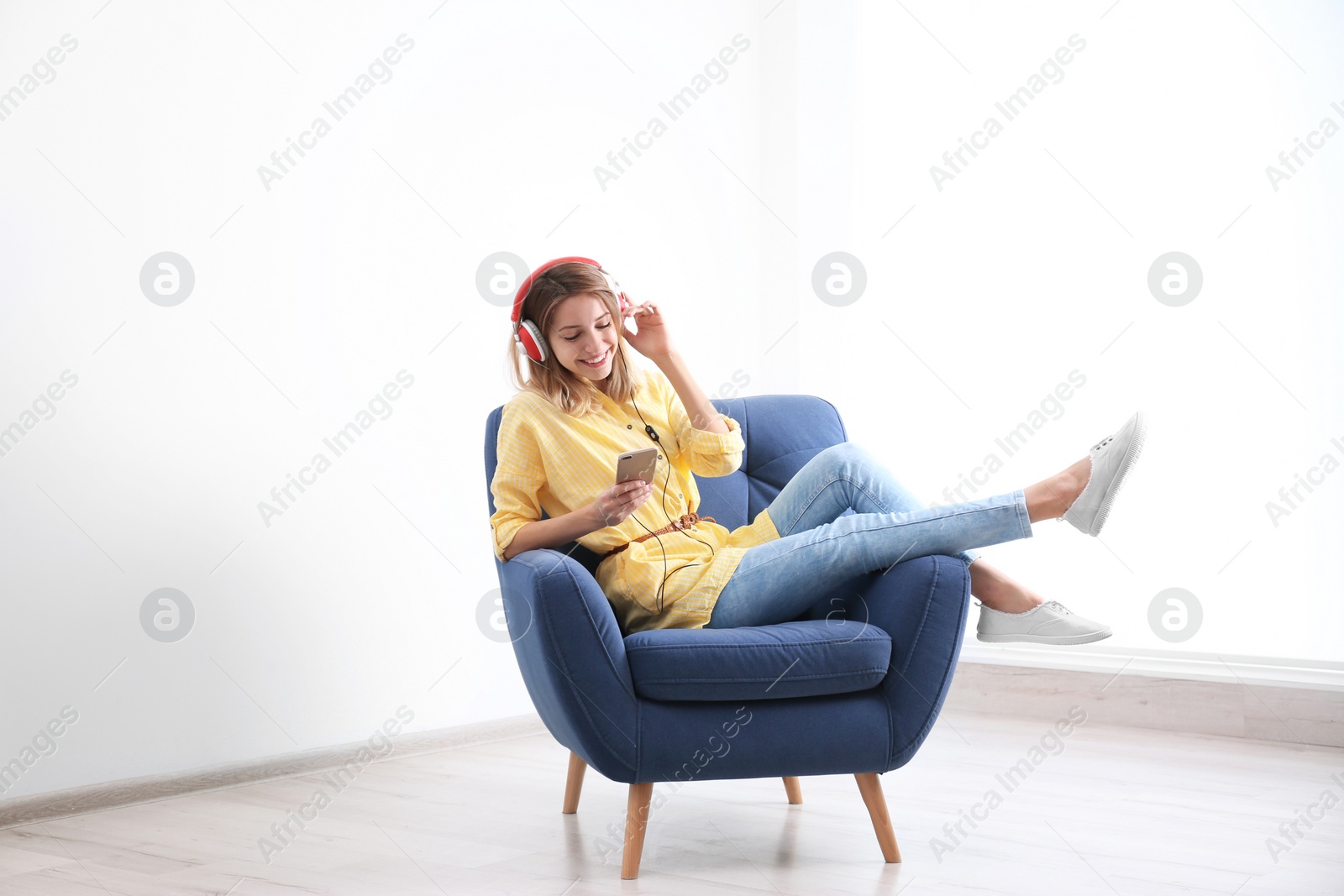 Photo of Young woman listening to music in armchair at home. Space for text