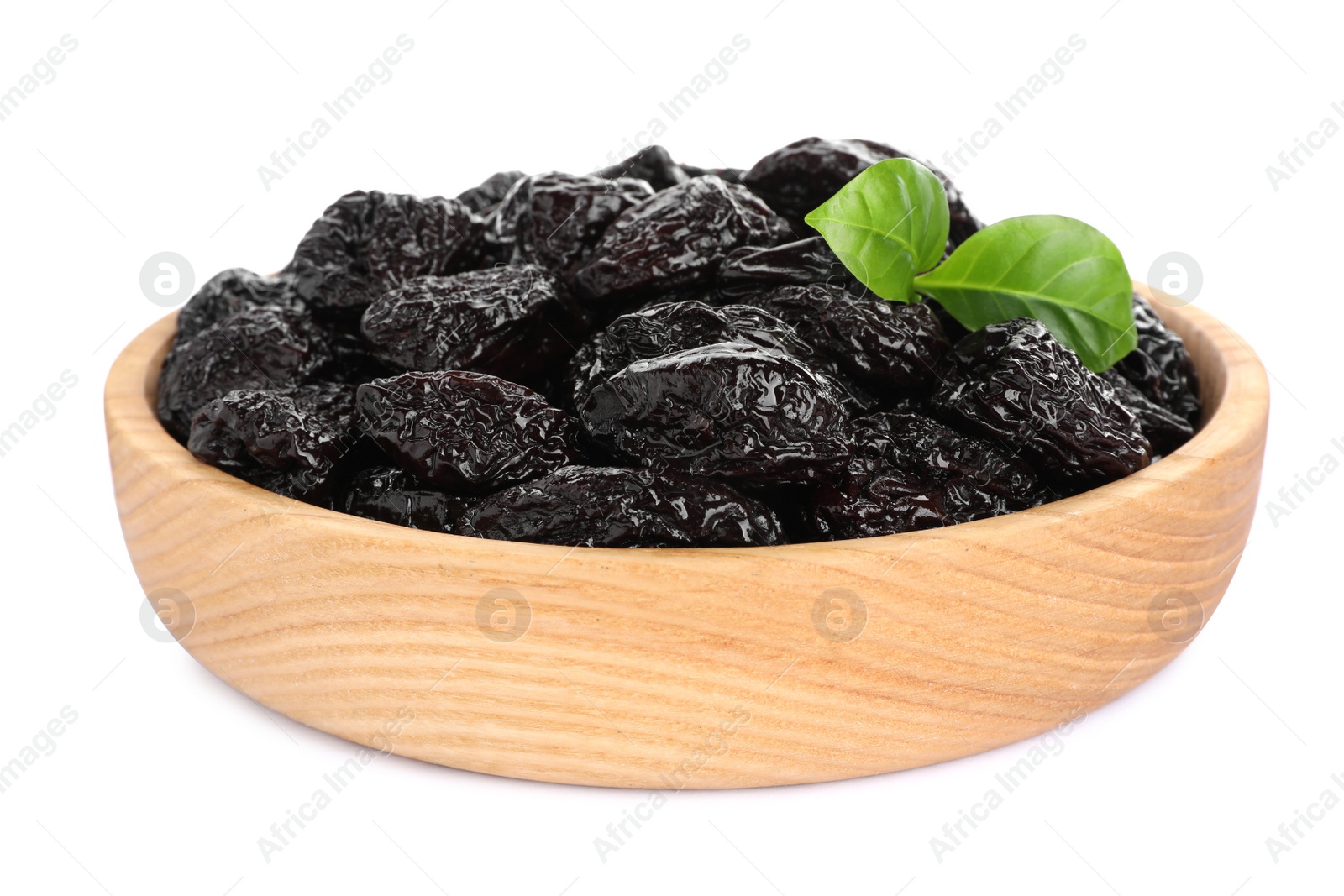 Photo of Wooden bowl with sweet dried prunes and green leaves isolated on white