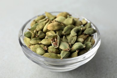 Bowl of dry cardamom pods on light table, closeup