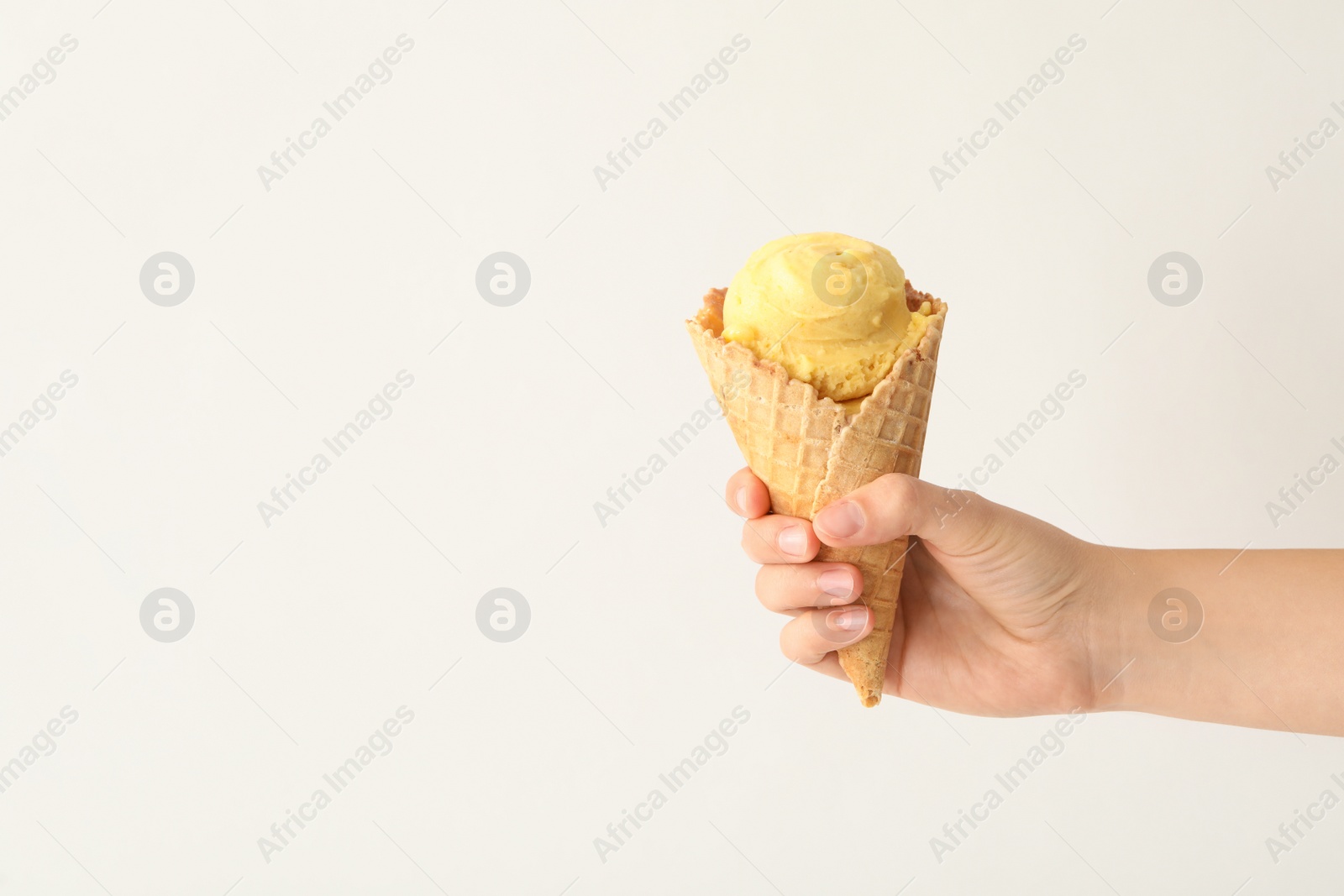 Photo of Woman holding waffle cone with delicious yellow ice cream on white background, closeup. Space for text