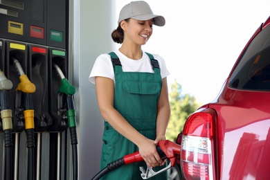 Young worker refueling car at modern gas station