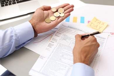 Photo of Tax accountant with money and documents at table