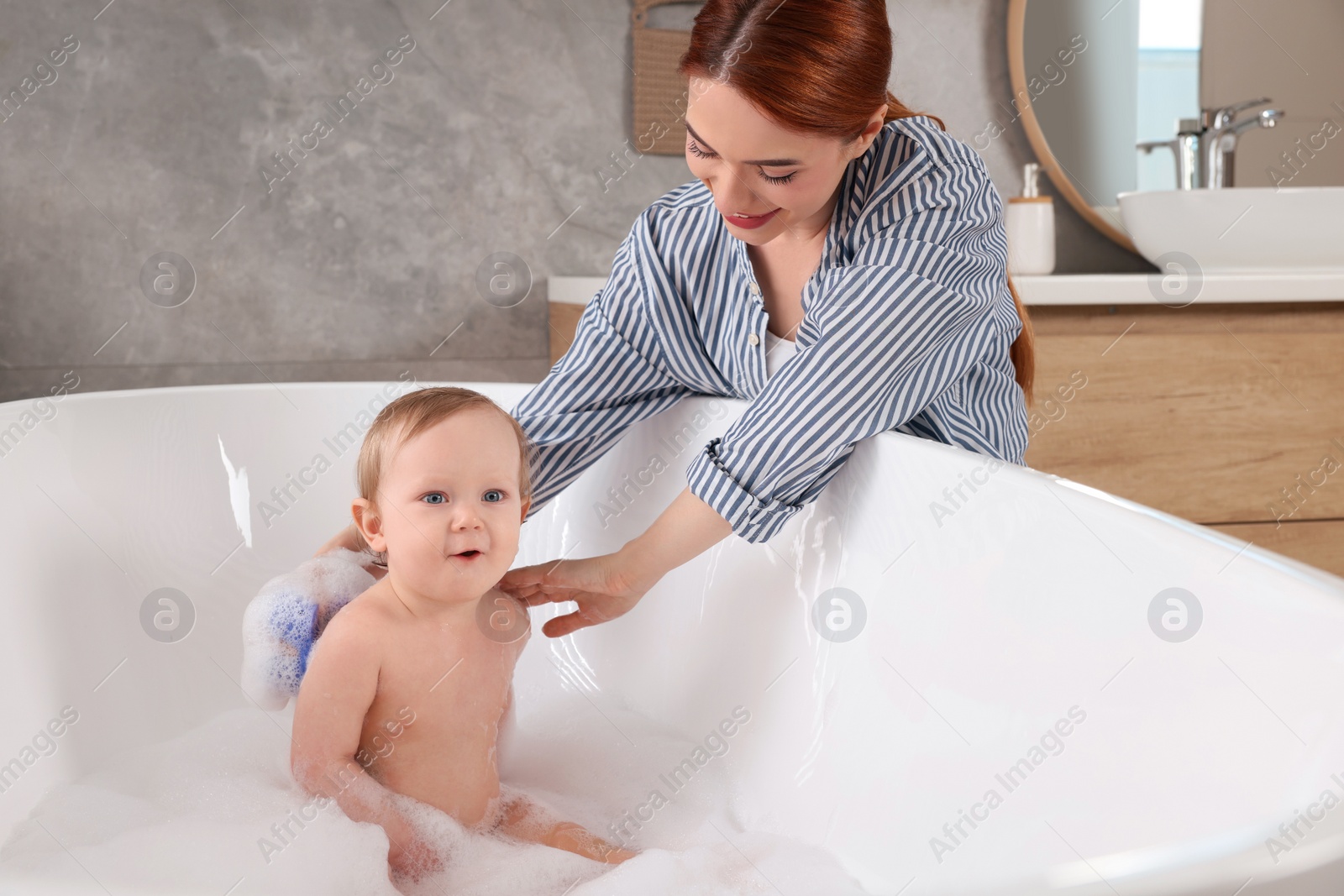 Photo of Mother washing her little baby in tub at home