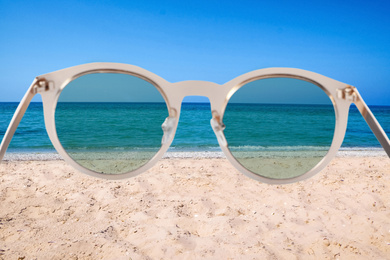 Sandy beach and sea on sunny day, view through sunglasses