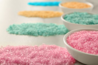 Many bowls with colorful sea salt on white table, closeup. Space for text