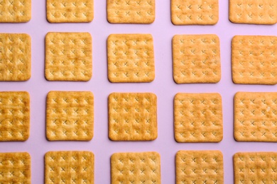 Delicious crackers on violet background, flat lay