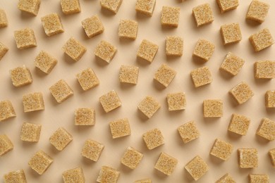 Photo of Brown sugar cubes on beige background, top view