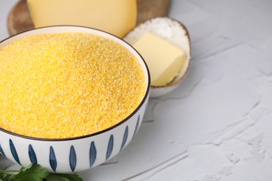 Photo of Raw cornmeal in bowl on light textured table, closeup. Space for text