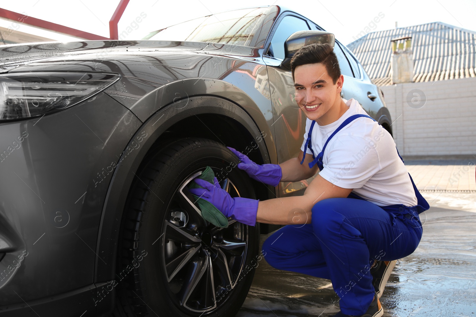 Photo of Male worker cleaning automobile with rag at car wash