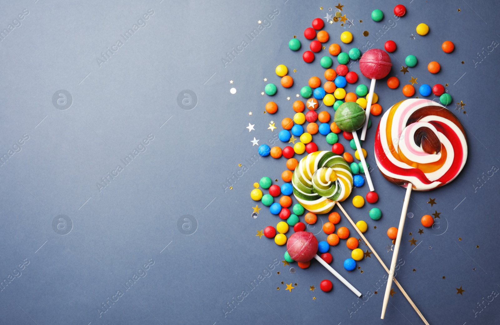 Photo of Lollipops and colorful candies on grey background, top view. Space for text