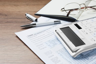 Photo of Calculator, documents and stationery on wooden table, closeup. Tax accounting