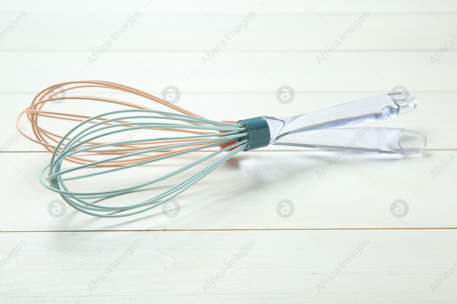 Photo of Two whisks on white wooden table, closeup