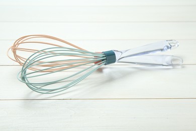 Two whisks on white wooden table, closeup