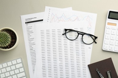 Accounting documents, glasses and houseplant on beige table, flat lay