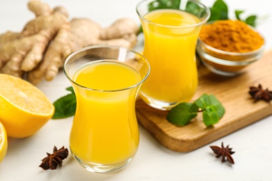 Immunity boosting drink and ingredients on white wooden table, closeup