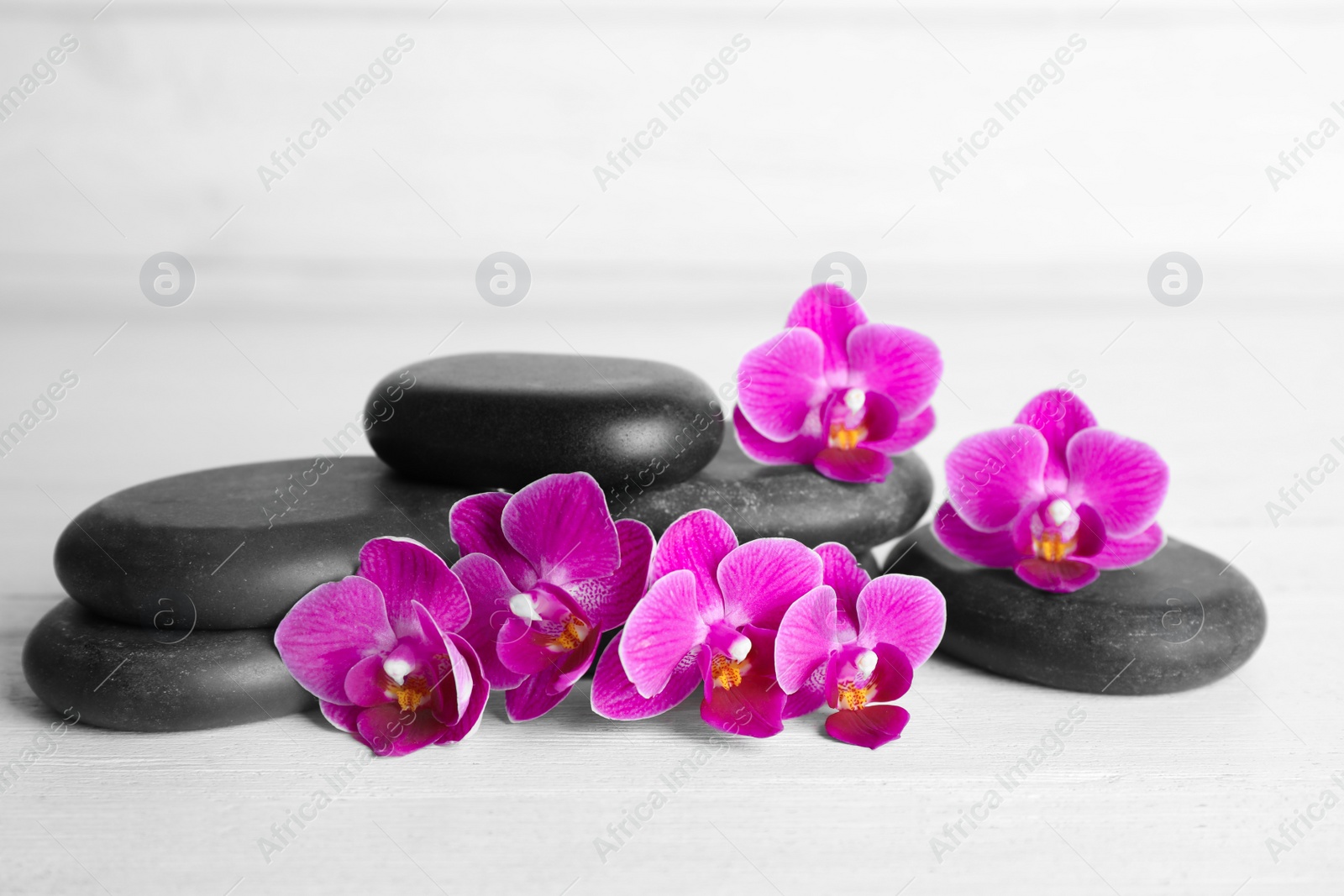 Photo of Spa stones and orchid flowers on white wooden table