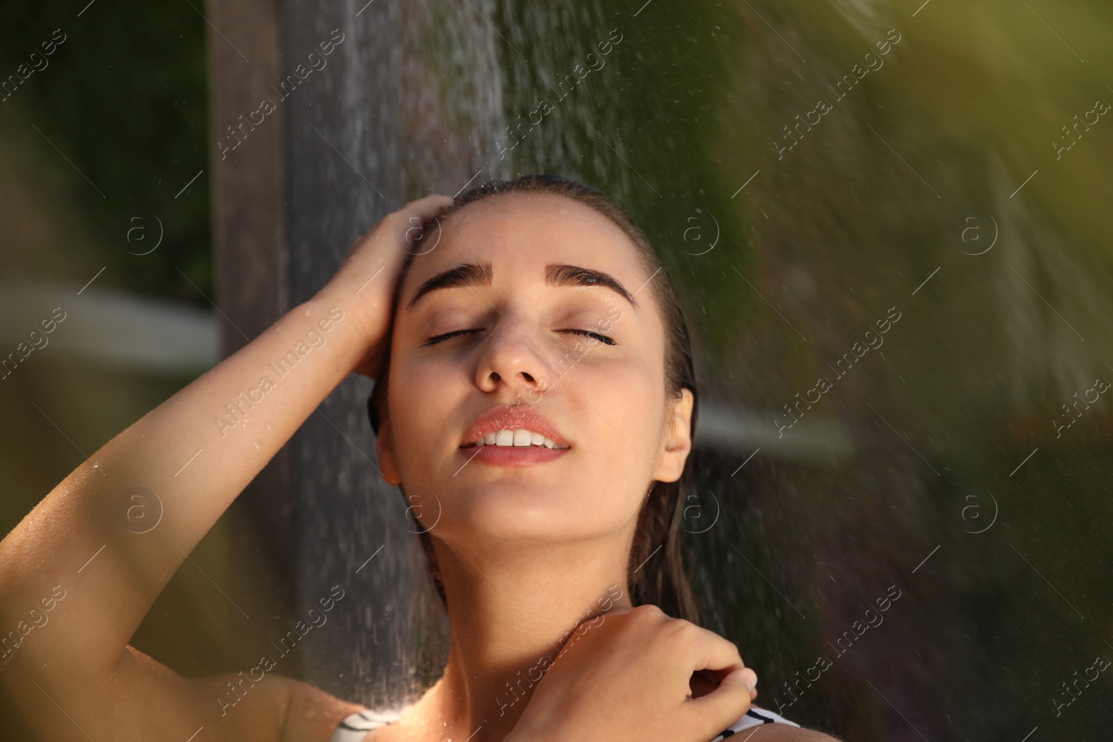 Photo of Woman washing hair in outdoor shower on summer day