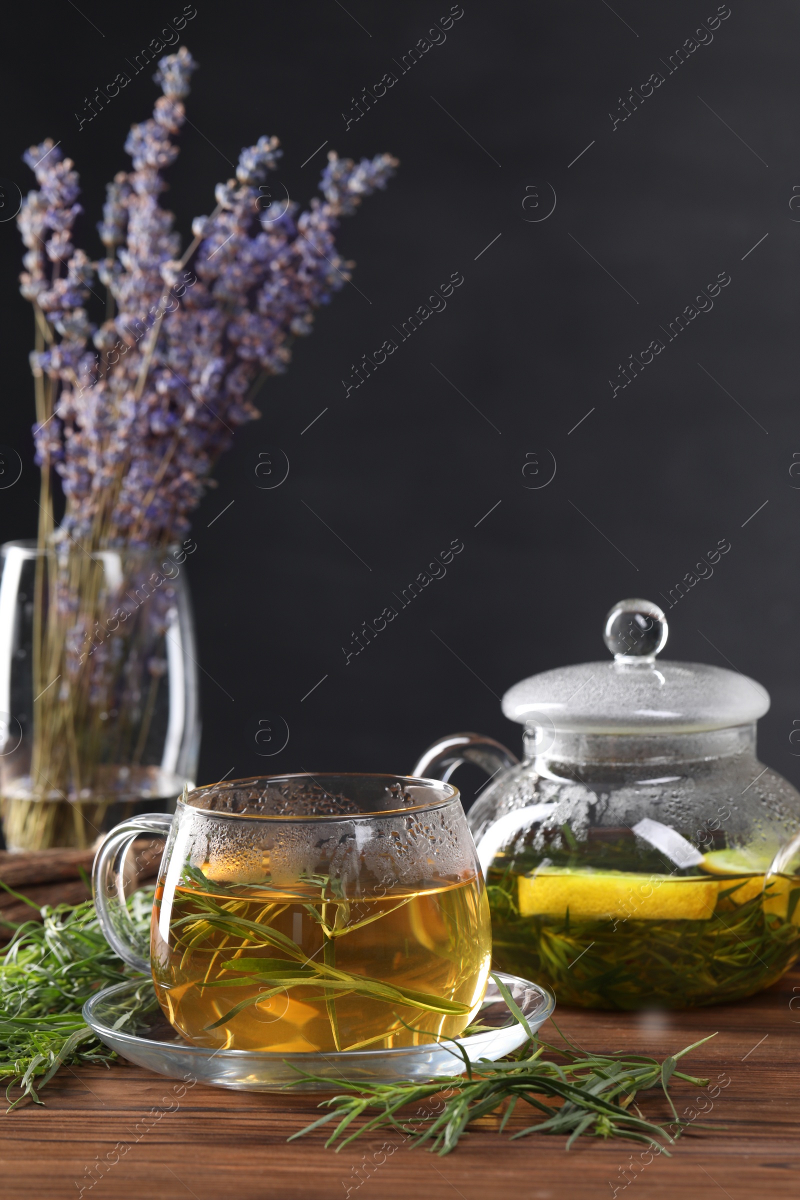 Photo of Homemade herbal tea and fresh tarragon leaves on wooden table